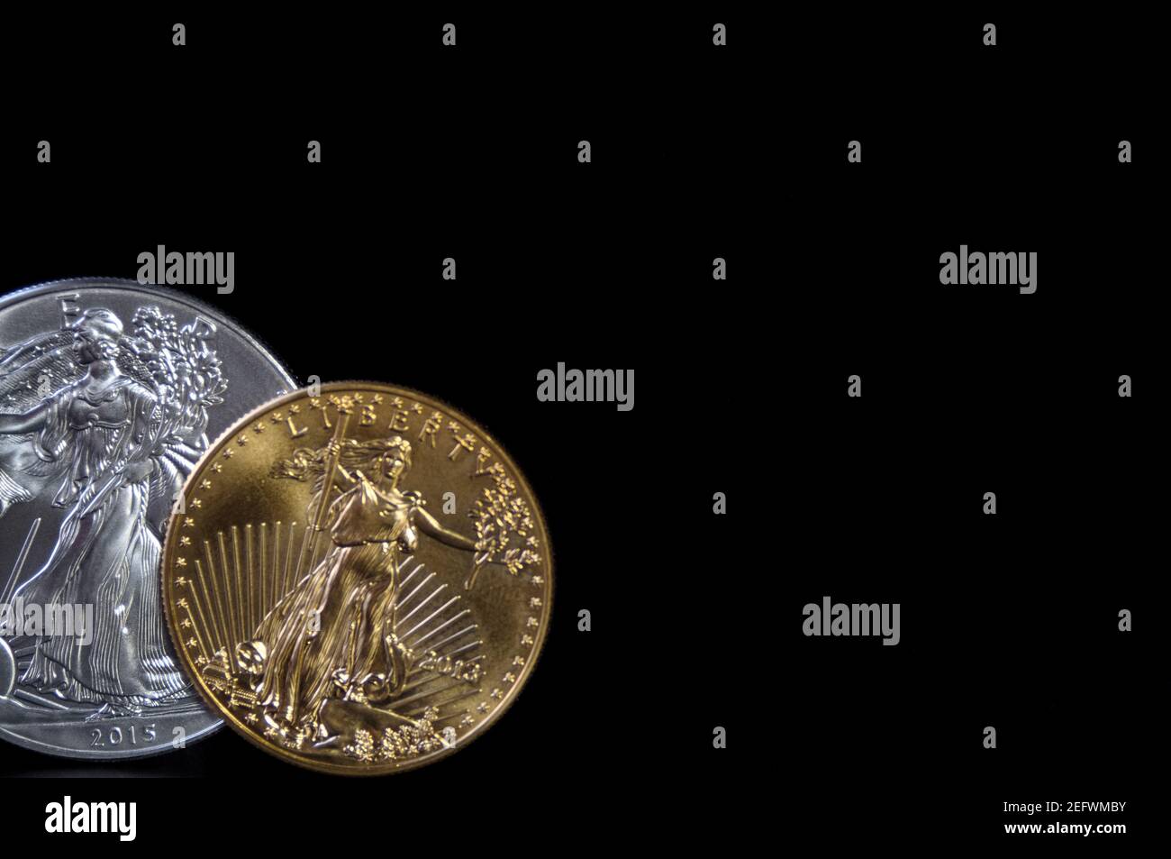 Eine 1 Unze Goldmünze und eine 1 Unze Silberadlermünze auf schwarzem Hintergrund, mit Kopierraum Stockfoto