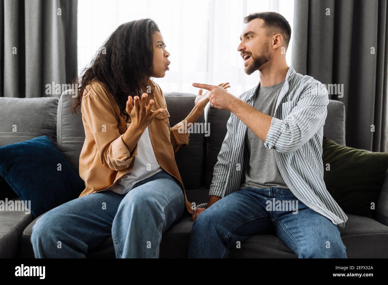Verheiratete junge Paar emotionale diskutieren über etwas, sie haben Problem. afroamerikanische Frau und kaukasischer Mann sind sich nicht einig haben ein Missverständnis, kann nicht entscheiden, ein Streit Stockfoto