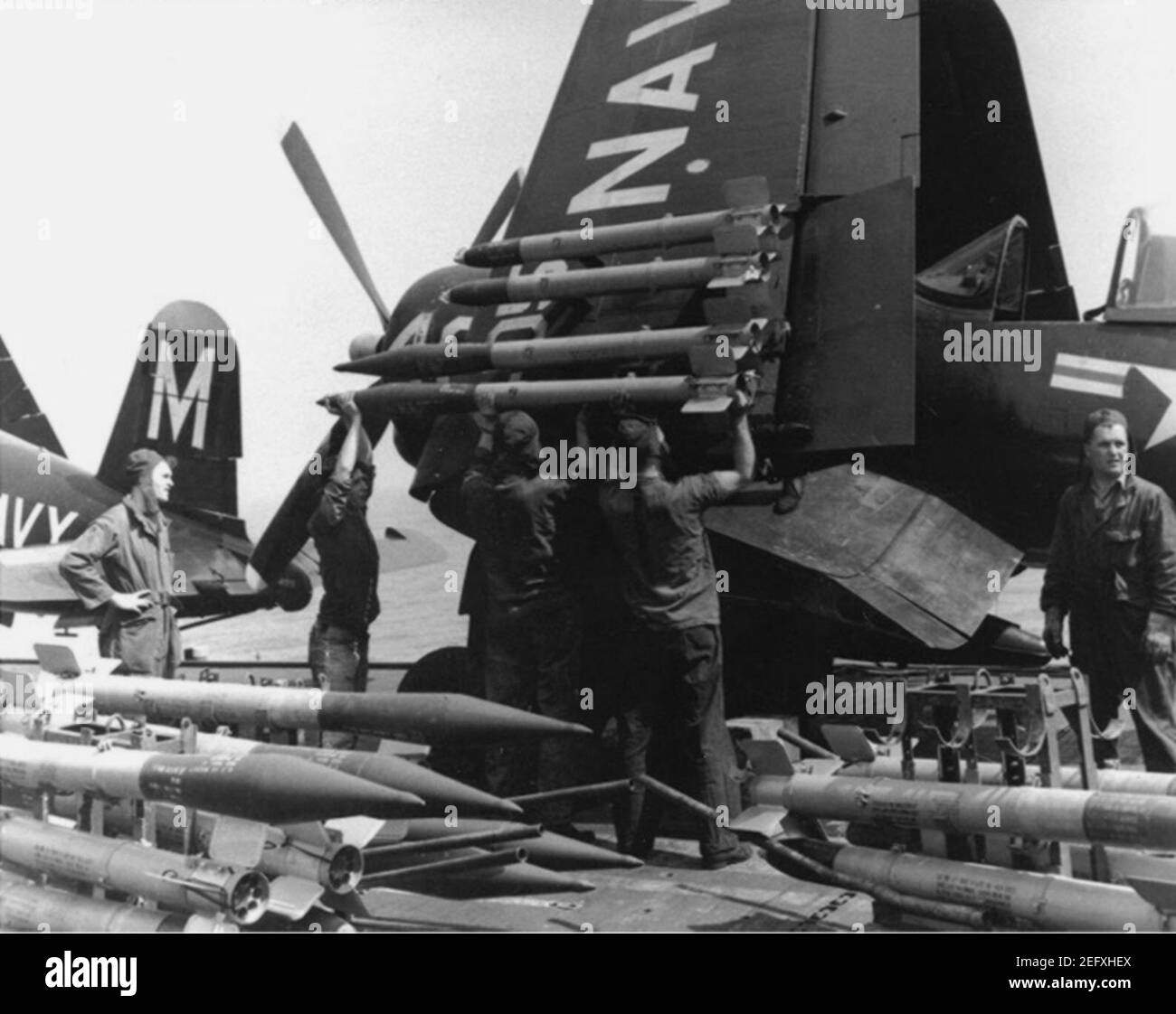 Ordnancemen laden Raketen auf eine Vought F4U-4B von VF-64 an Bord USS Philippine Sea (CV-47) am 21. Mai 1951 Stockfoto