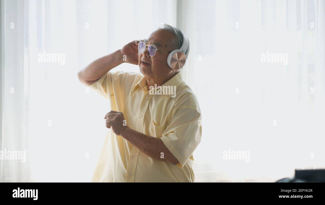 Asiatischer älterer Mann oder Opa, glücklicher älterer Rentner mit Kopfhörern Musik Radio hören und bewegenden Tanz genießen jeden Moment seiner lustigen lif Stockfoto