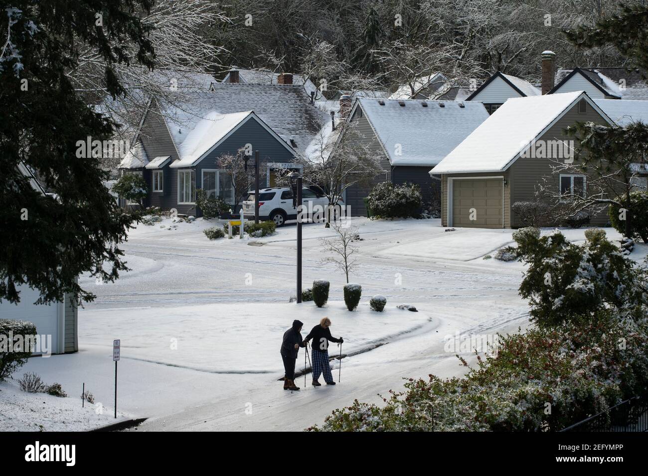 Ältere Paare gehen am 15. Februar 2021 mit Vorsicht auf der vereisten Straße in Lake Oswego, Oregon, nachdem Schnee und eiskalter Regen die Gegend um Portland erreicht haben. Stockfoto