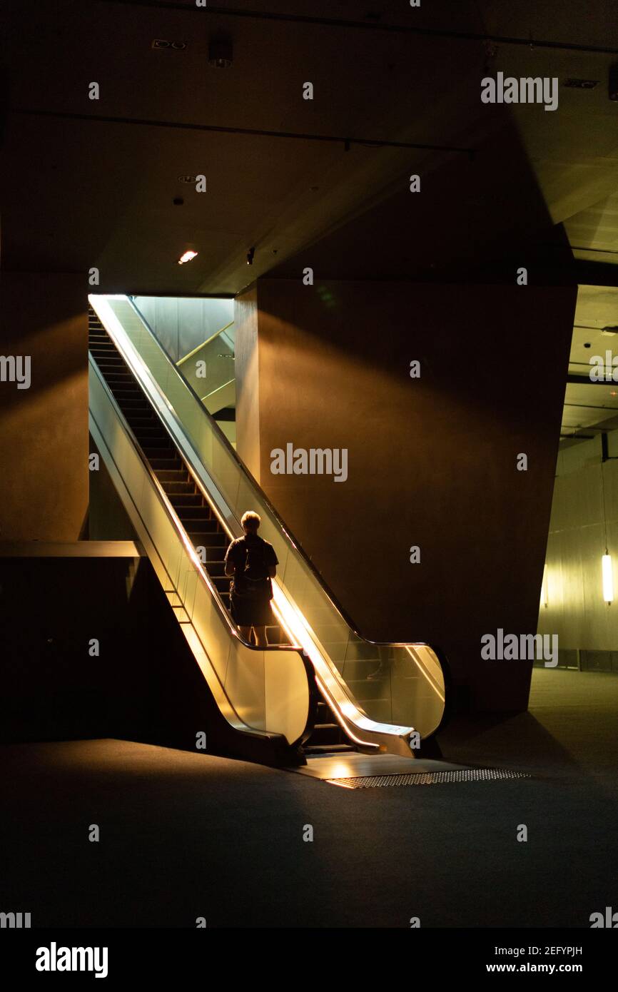 Ein Mann fährt auf einer unheimlich beleuchteten Rolltreppe in Melborne, Australien Stockfoto