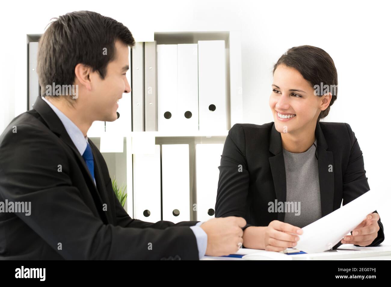 Schöne Geschäftsfrau lächelt zu ihrem Kollegen bei der Sitzung Stockfoto