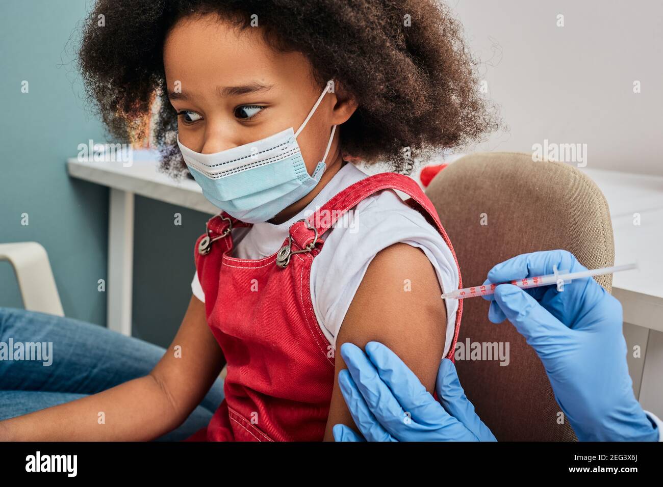 Afroamerikanisches weibliches Kind während der Impfung in der Arztpraxis. Impfung von Kindern während einer globalen Pandemie Stockfoto