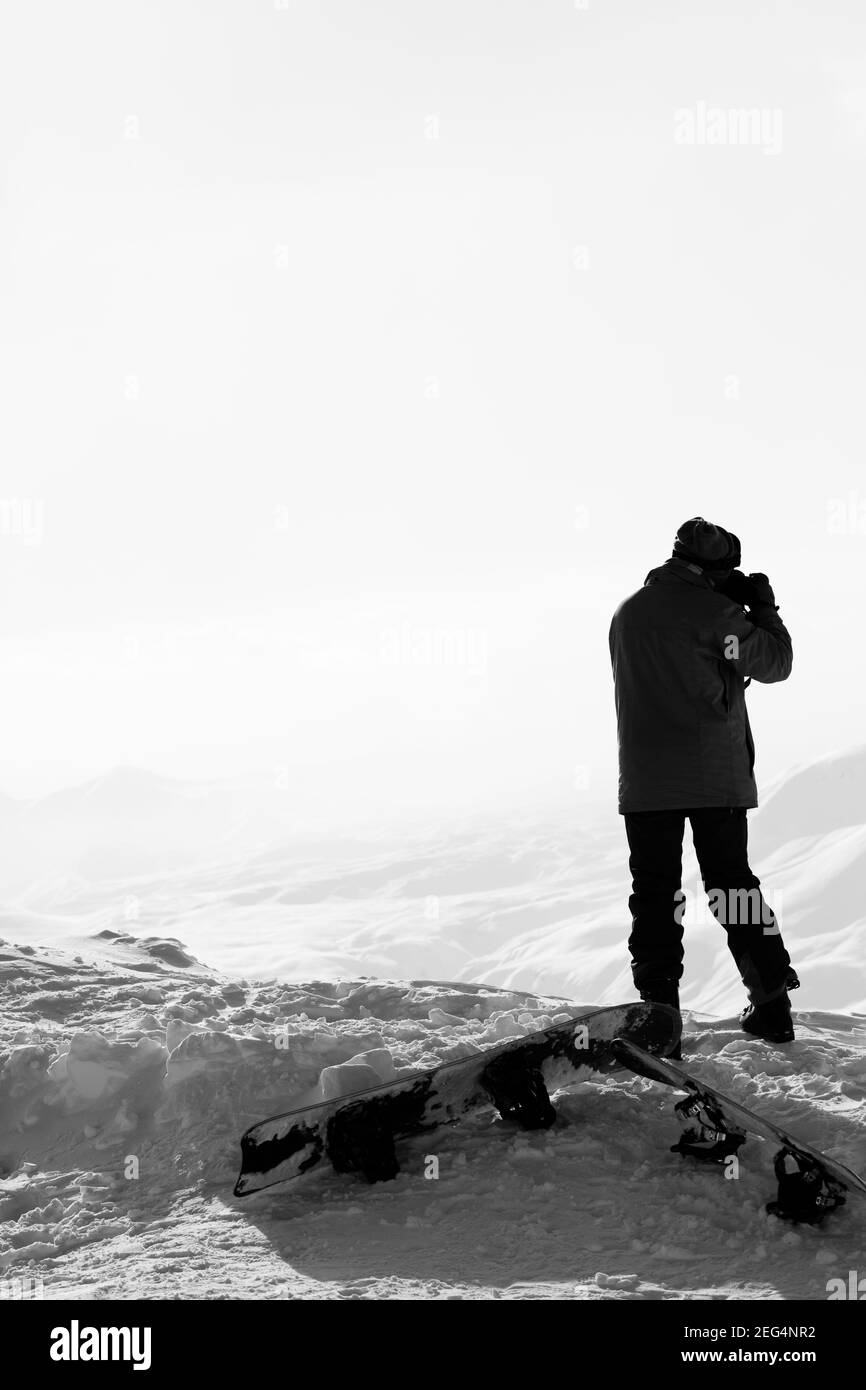 Skifahrer macht Foto mit der Kamera auf dem schneebedeckten Berg im Nebel. Kaukasus im Winter, Georgien, Region Gudauri. Schwarzweißbild. Hoch Stockfoto