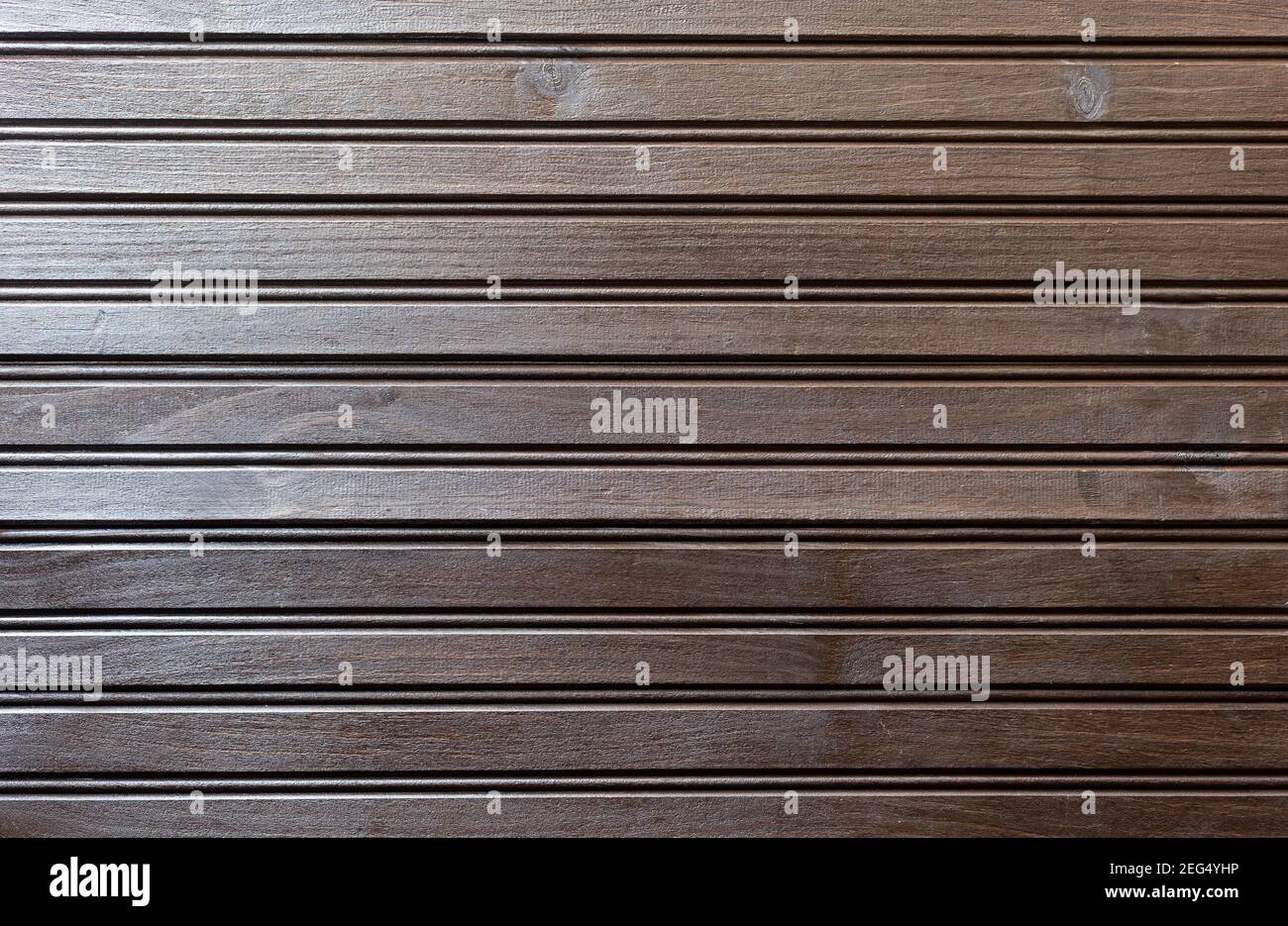 Eine dunkle Holzoberfläche aus schmalen Brettern in horizontaler Position. Seitenlicht tritt ein. Hintergrund für Einladungen oder Karten für Veranstaltungen wie Hochzeiten Stockfoto