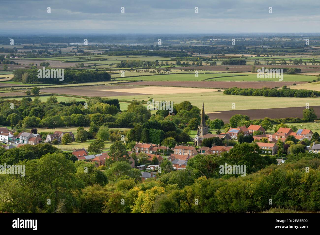 Landschaftlich schöner Blick auf das Dorf Bishop Wilton (Häuser und Kirche) & offene, flach liegende Felder im Tal von York - Yorkshire Wolds, East Riding, England Großbritannien. Stockfoto