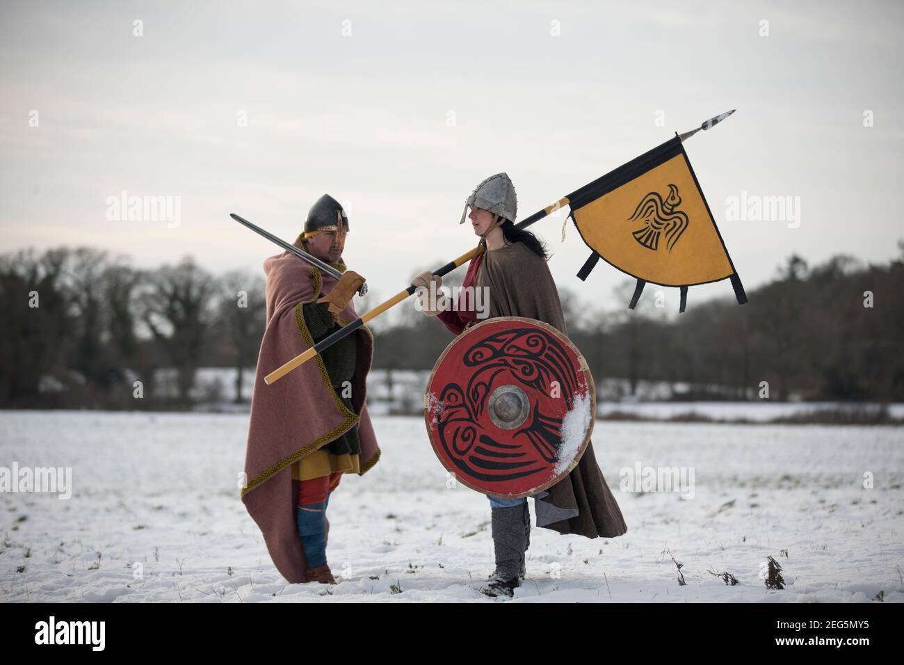 Viking Schild Maid, trägt Rabe gescheut und Banner, steht in Freundschaft mit angelsächsischen Krieger in gefrorener Landschaft. Stockfoto