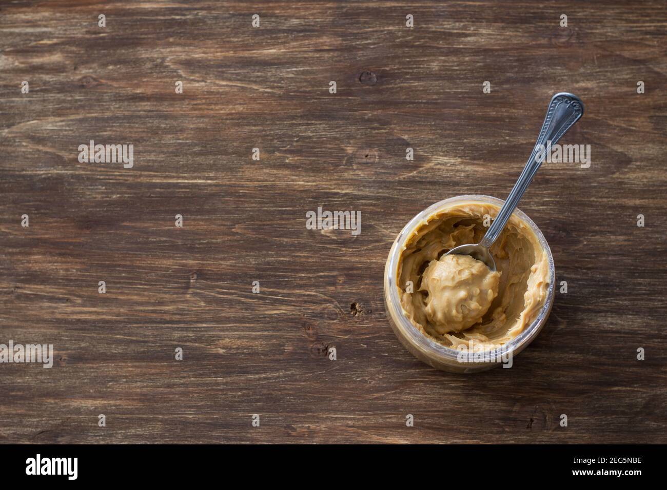 Glas mit Erdnussbutter auf einem Holztisch, Draufsicht, Freiraum Stockfoto