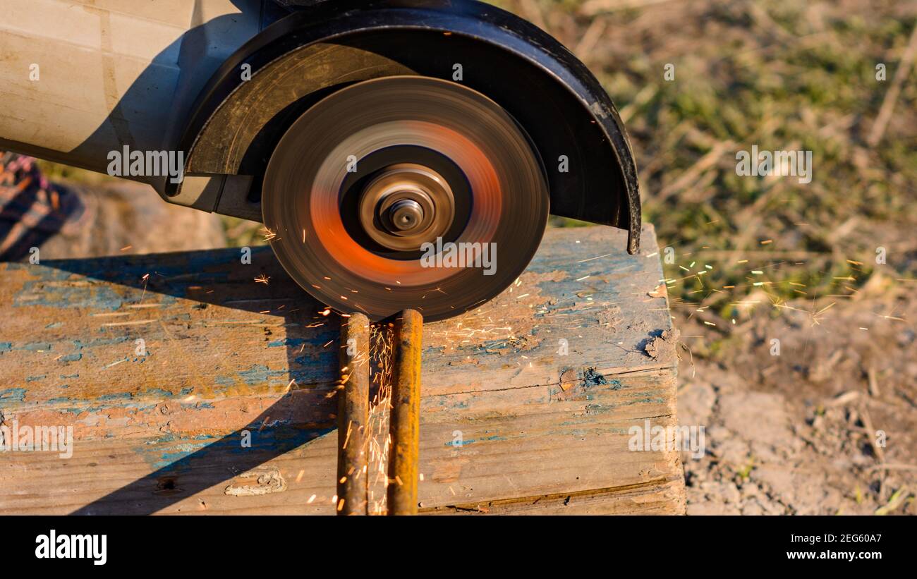 Der Arbeiter schneidet das Metall mit einem Winkelschleifer, die Arbeit wird am street,2020 durchgeführt Stockfoto