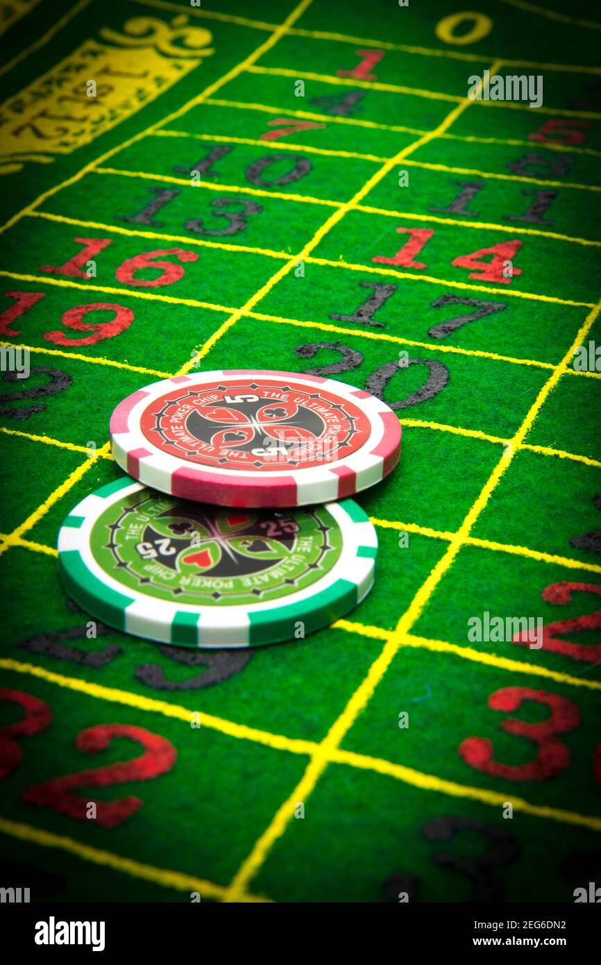 Glücksspiel Chips, FranceColorful Casino Chips auf einem pulsierenden Roulette-Tisch während eines Abendspiels in einer belebten Spielhalle Stockfoto