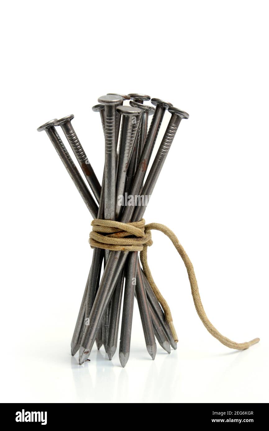 Bündel Metallnägel, die mit Garn vor weißem Hintergrund zusammengebunden sind Stockfoto