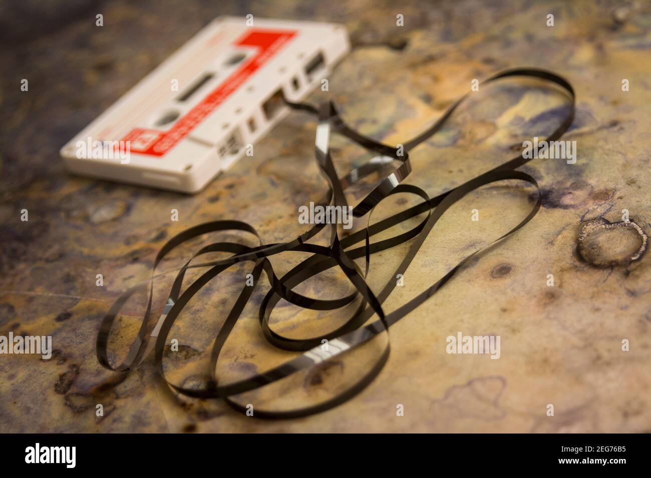 Altes Kassettenband mit verwickeltem Band, das auf einer strukturierten Oberfläche liegt und Nostalgie für Vintage-Musik weckt Stockfoto