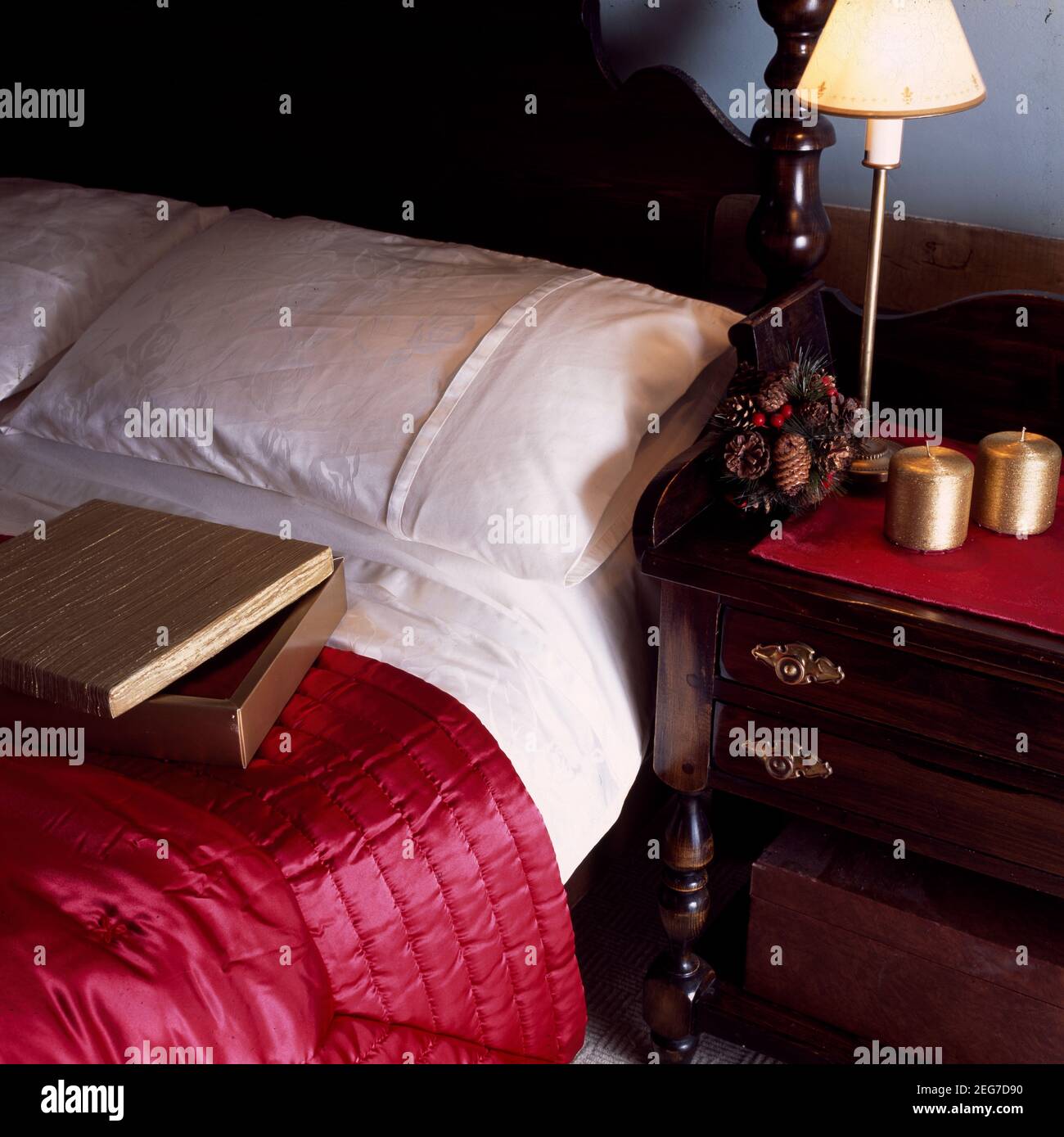 Nahaufnahme von weißer Bettwäsche und roter Arbeitsscheibe mit Bettbeleuchtung Stockfoto