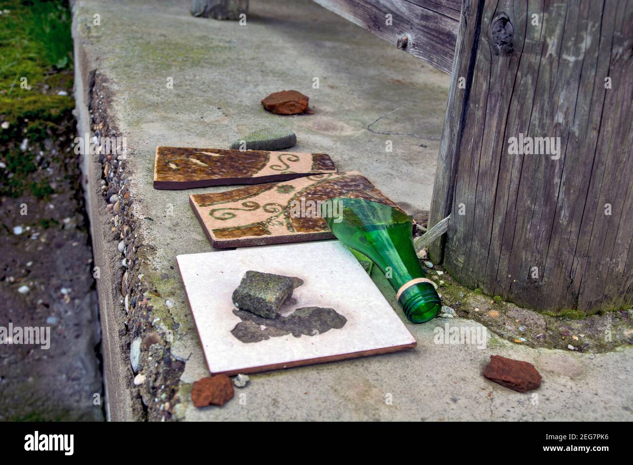 Ein altes verlassenes Haus und eine zerbrochene Glasflasche und Fliesen auf der Eingangsterrasse des gleichen. Stockfoto