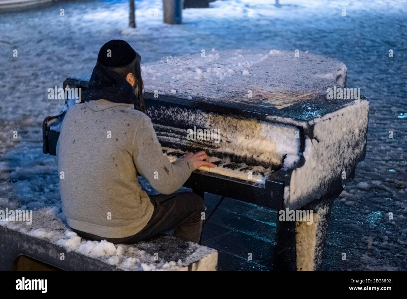 JERUSALEM, ISRAEL - FEBRUAR 17: Ein junger orthodoxer jüdischer Mann spielt am Zion-Platz Klavier, während Schneefall am 17. Februar 2020 in Jerusalem, Israel. Jerusalem bedeckt durch ersten Schnee in sechs Jahren erreicht sieben bis 10 Zentimeter (drei bis vier Zoll) über Nacht. Stockfoto