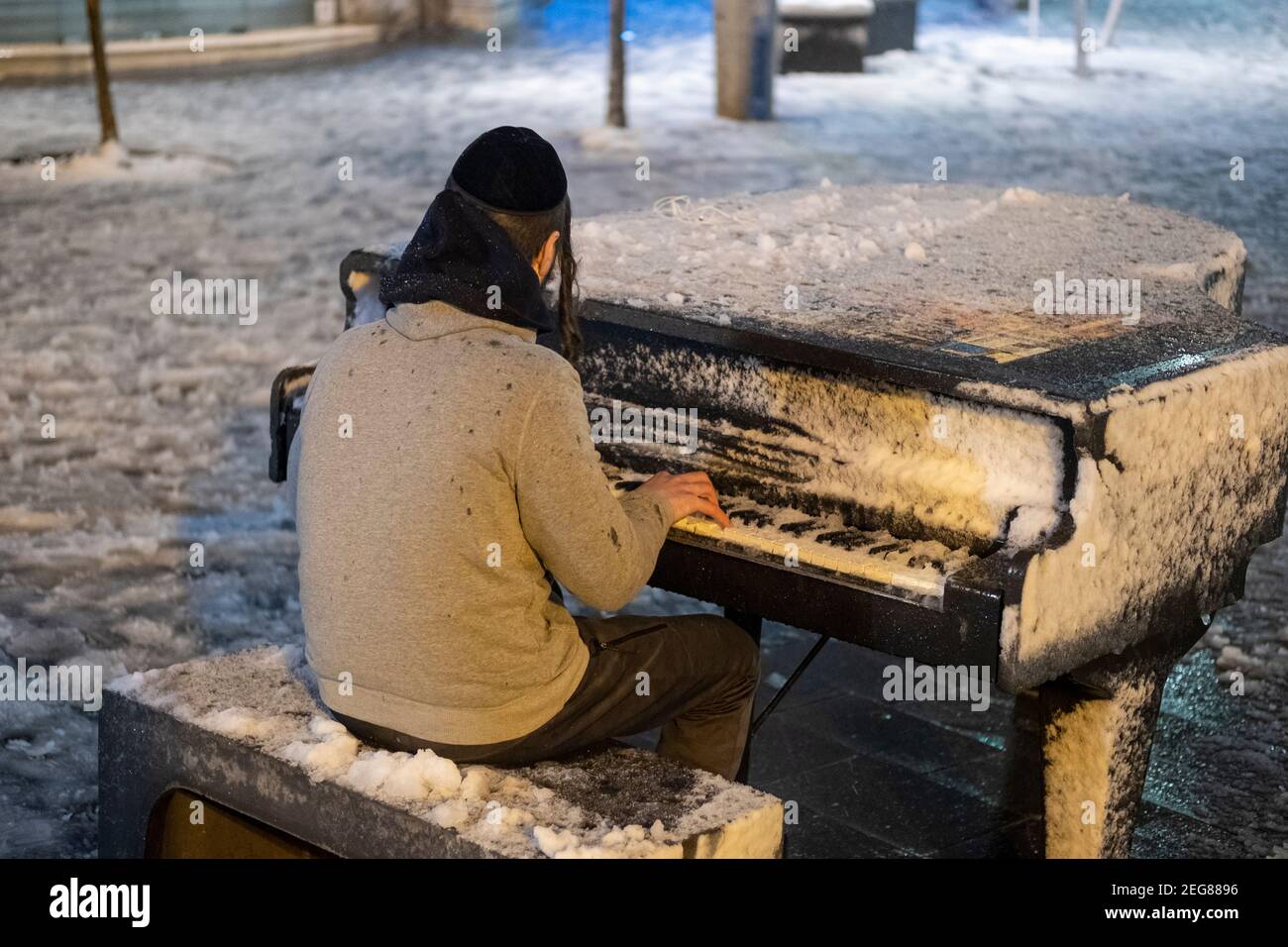 JERUSALEM, ISRAEL - FEBRUAR 17: Ein junger orthodoxer jüdischer Mann spielt am Zion-Platz Klavier, während Schneefall am 17. Februar 2020 in Jerusalem, Israel. Jerusalem bedeckt durch ersten Schnee in sechs Jahren erreicht sieben bis 10 Zentimeter (drei bis vier Zoll) über Nacht. Stockfoto