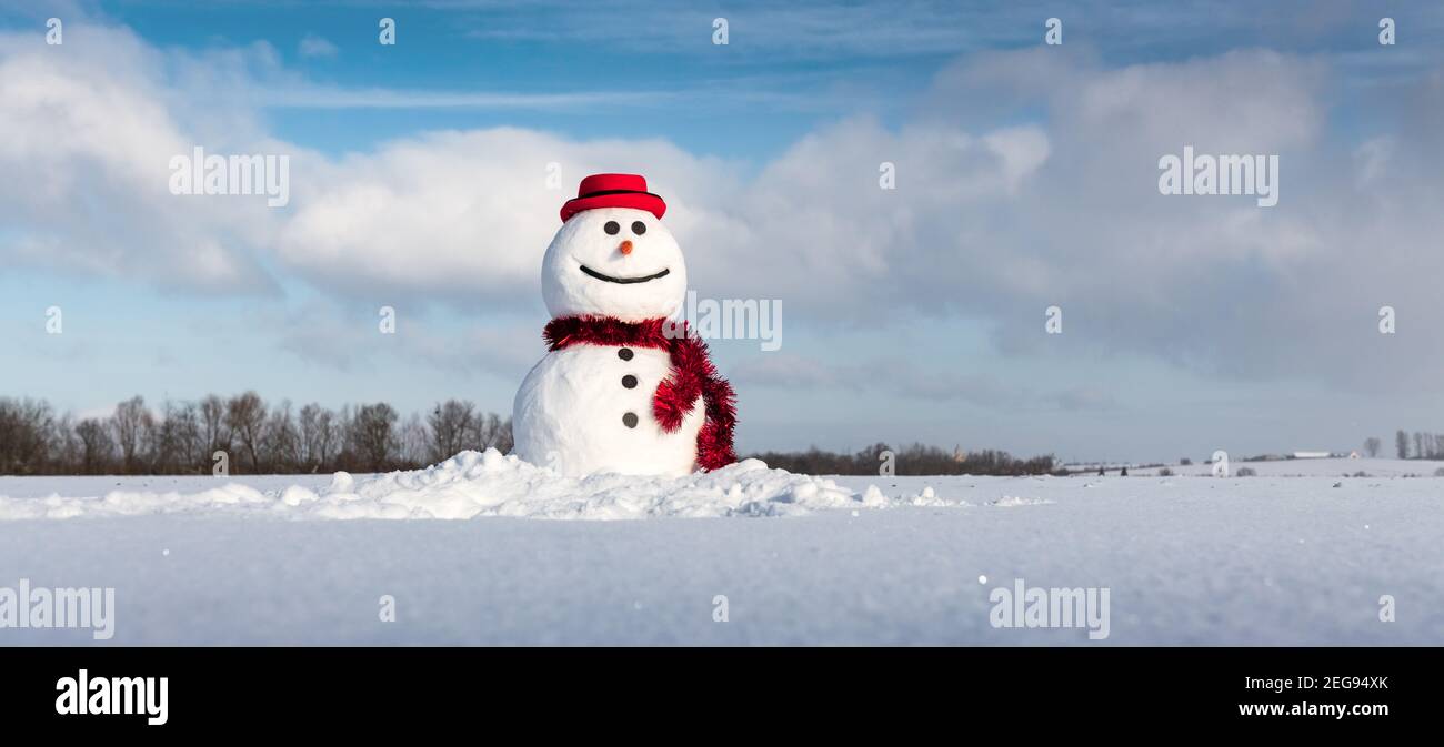 Lustige Schneemann in stilvollen roten Hut und roten Skalf auf schneebedeckten Feld. Panoramabilder ideal für das Mockup des Seitenkopfes Stockfoto