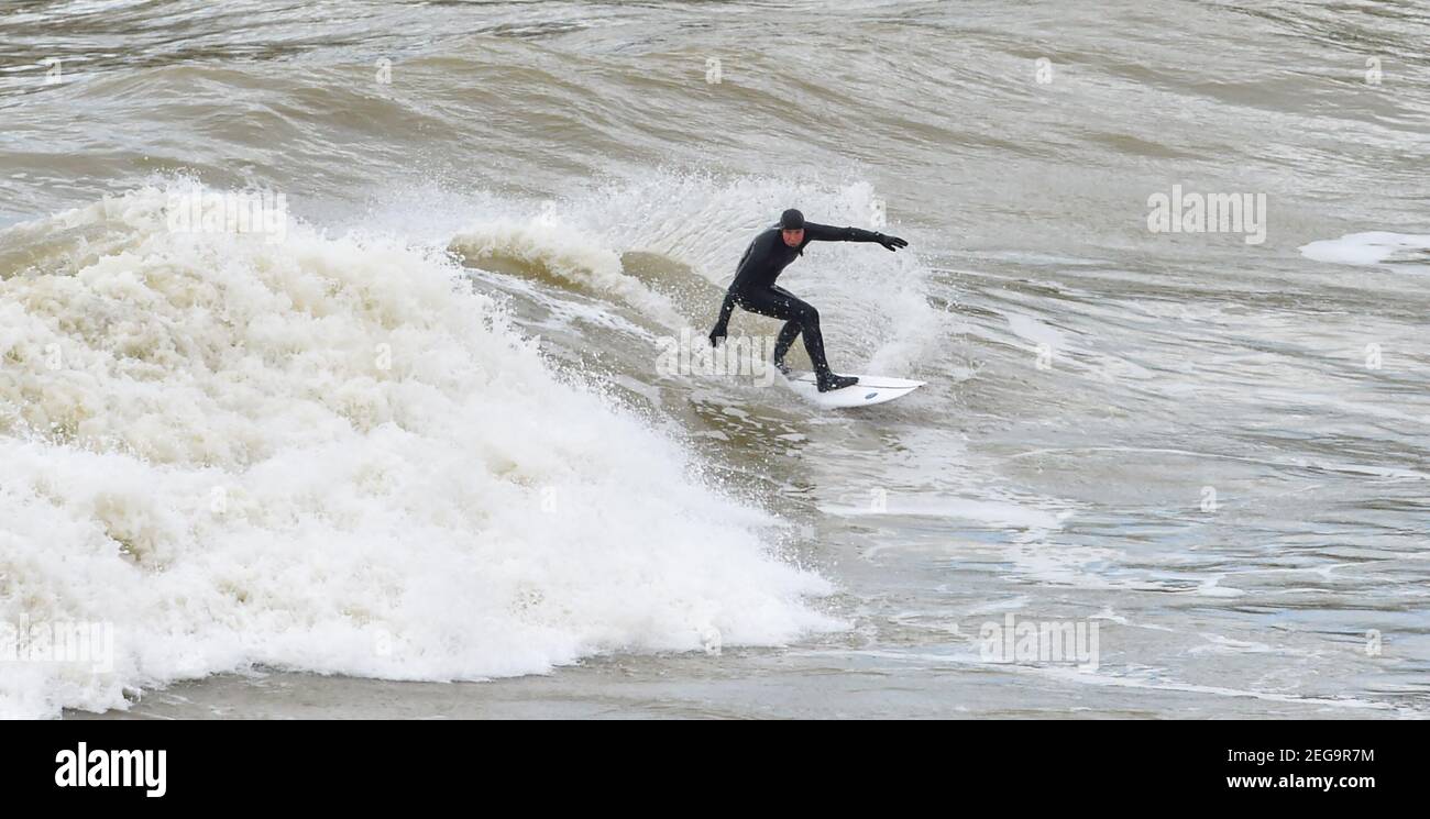 Brighton UK 18th February 2021 - Surfers fangen die Wellen von Brighton Marina an einem luftigen Tag entlang der Südküste mit starken Winden, die für Teile von Großbritannien morgen prognostiziert werden : Credit Simon Dack / Alamy Live News Stockfoto