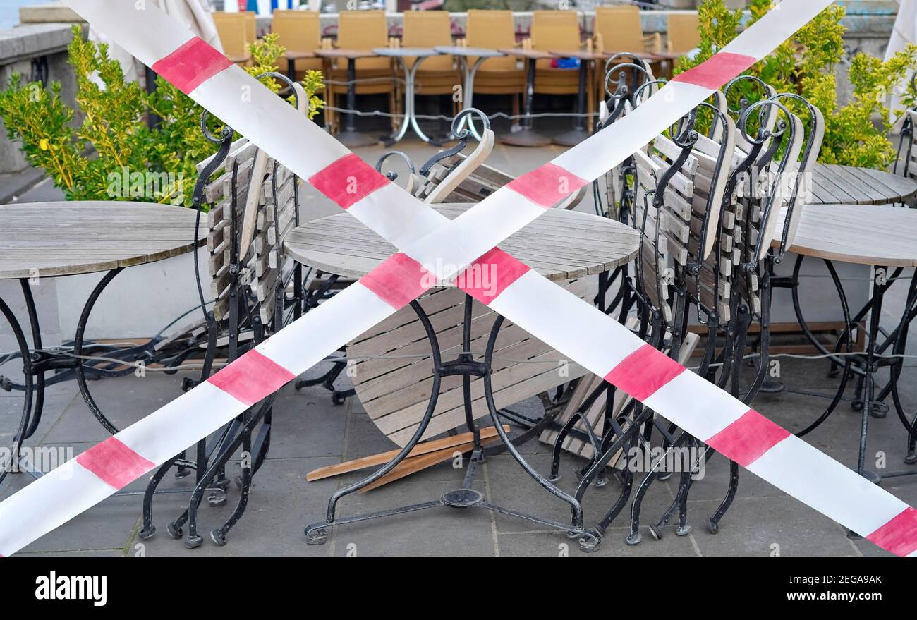 Gastronomie Lockdown wegen Corona Epidemie, geschlossene Restaurant Terrasse, Stühle, Tische und Barriere Band, symbolisch Stockfoto