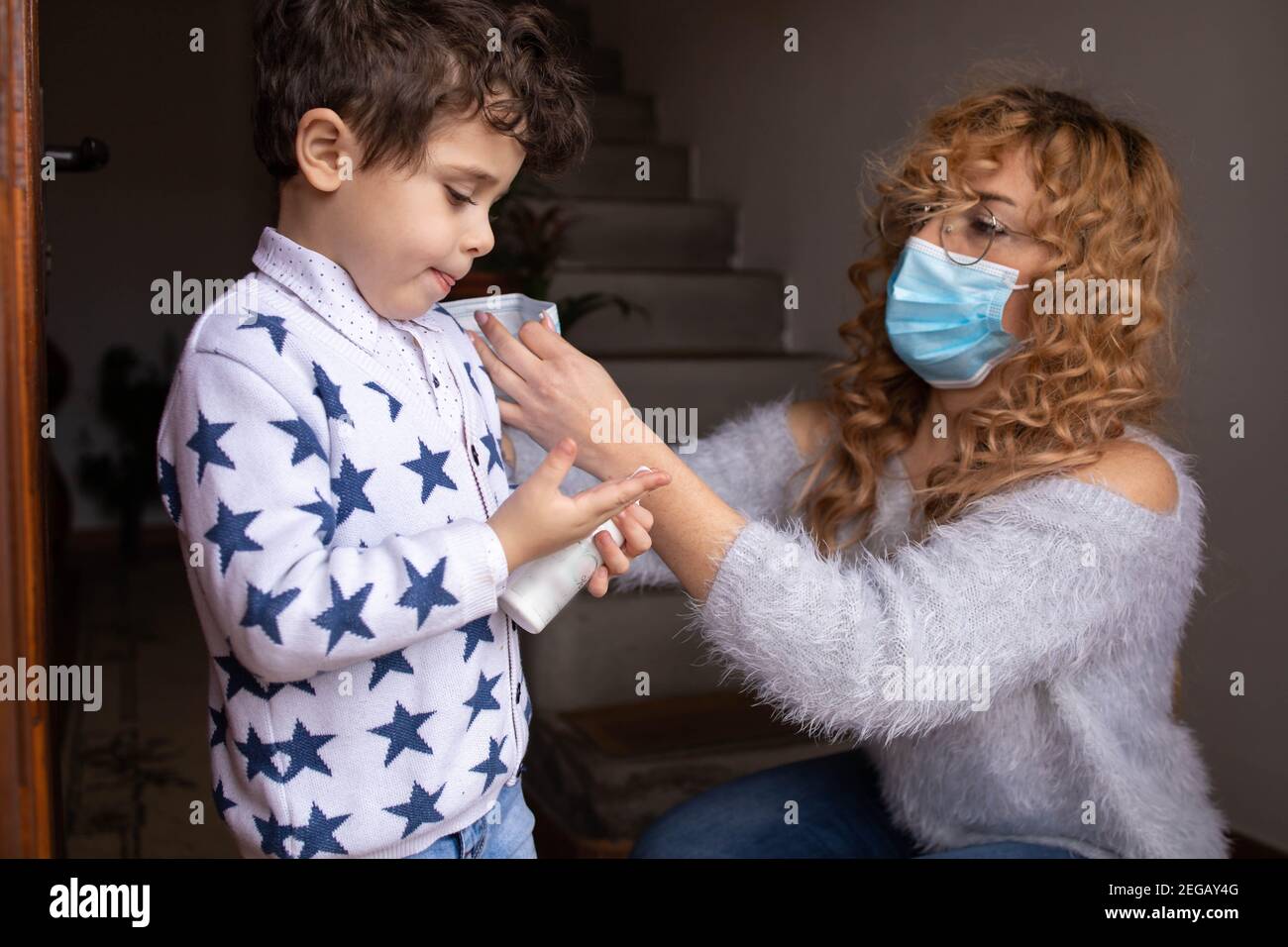 Mutter, die eine Maske auf das Gesicht ihres Sohnes setzt. Covid-Prävention Stockfoto