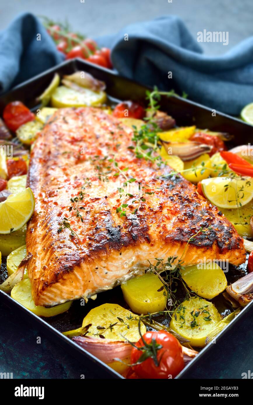 Großes saftiges Lachsfilet mit einer Chili-Honig-Marinade, gebacken mit Gemüse und heiß aus dem Ofen auf einem Backblech serviert Stockfoto