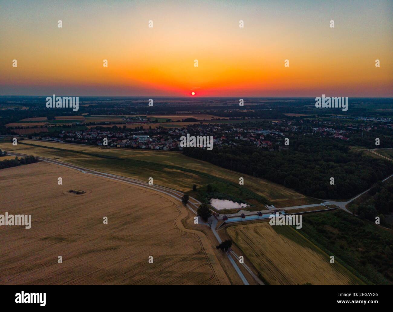 Luftaufnahme zur aufgehenden Sonne über Feldern, Dorf und Wald ohne Wolkenvormittag Stockfoto