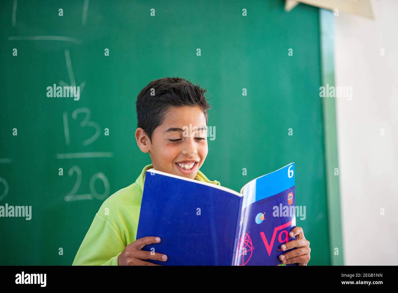 Kleiner Junge, der in einem Schulklassenzimmer laut vorliest Stockfoto