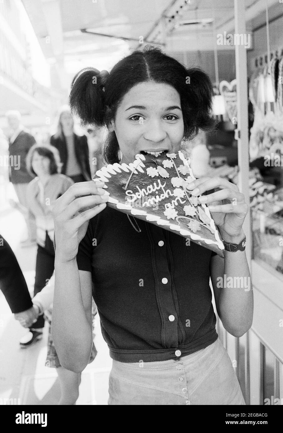 Porträt der deutschen Schlager- Disco- und Popsängerin Ramona Wulf während sie an einem Lebenskuchenherz abbeißt, Deutschland ca. 1972. Portrait der deutschen Pop-, Disco- und Popsängerin Ramona Wulf mit Lebkuchenherz, Deutschland ca. 1972. Stockfoto
