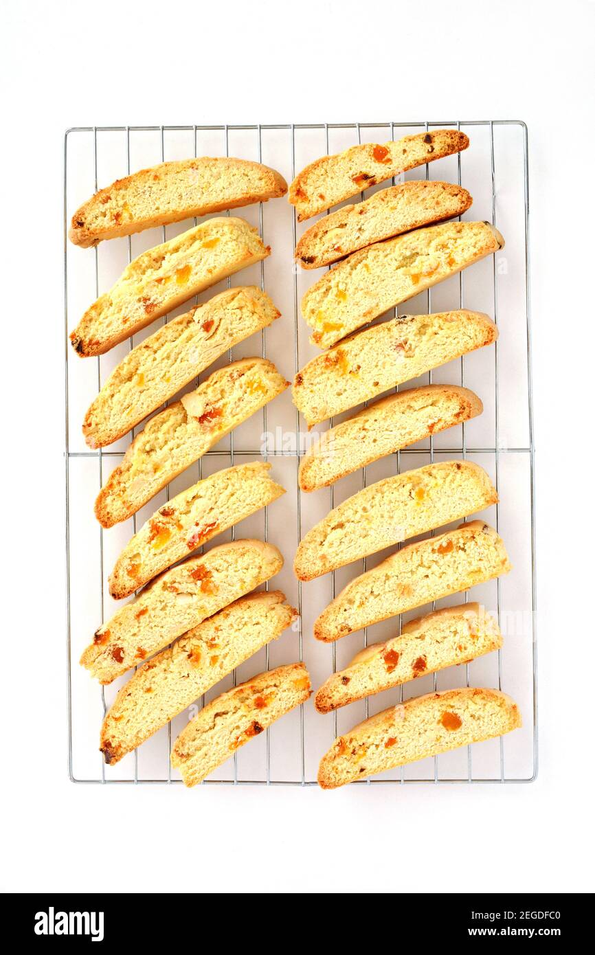 Hausgemachte Mandel-Aprikosen-Biscotti frisch aus dem Ofen auf Kühlregal auf weißem Hintergrund. Flache Lay-Komposition im vertikalen Format. Stockfoto