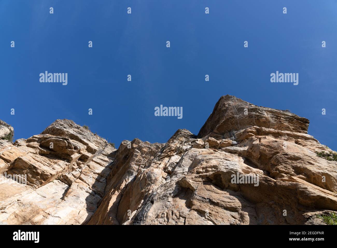 Steile Klippe mit Schutzdrahtgeflecht gegen herabfallende Felsen aus den Bergen. Klettern Hobby, Sport. Schwieriger und gefährlicher Sport Stockfoto