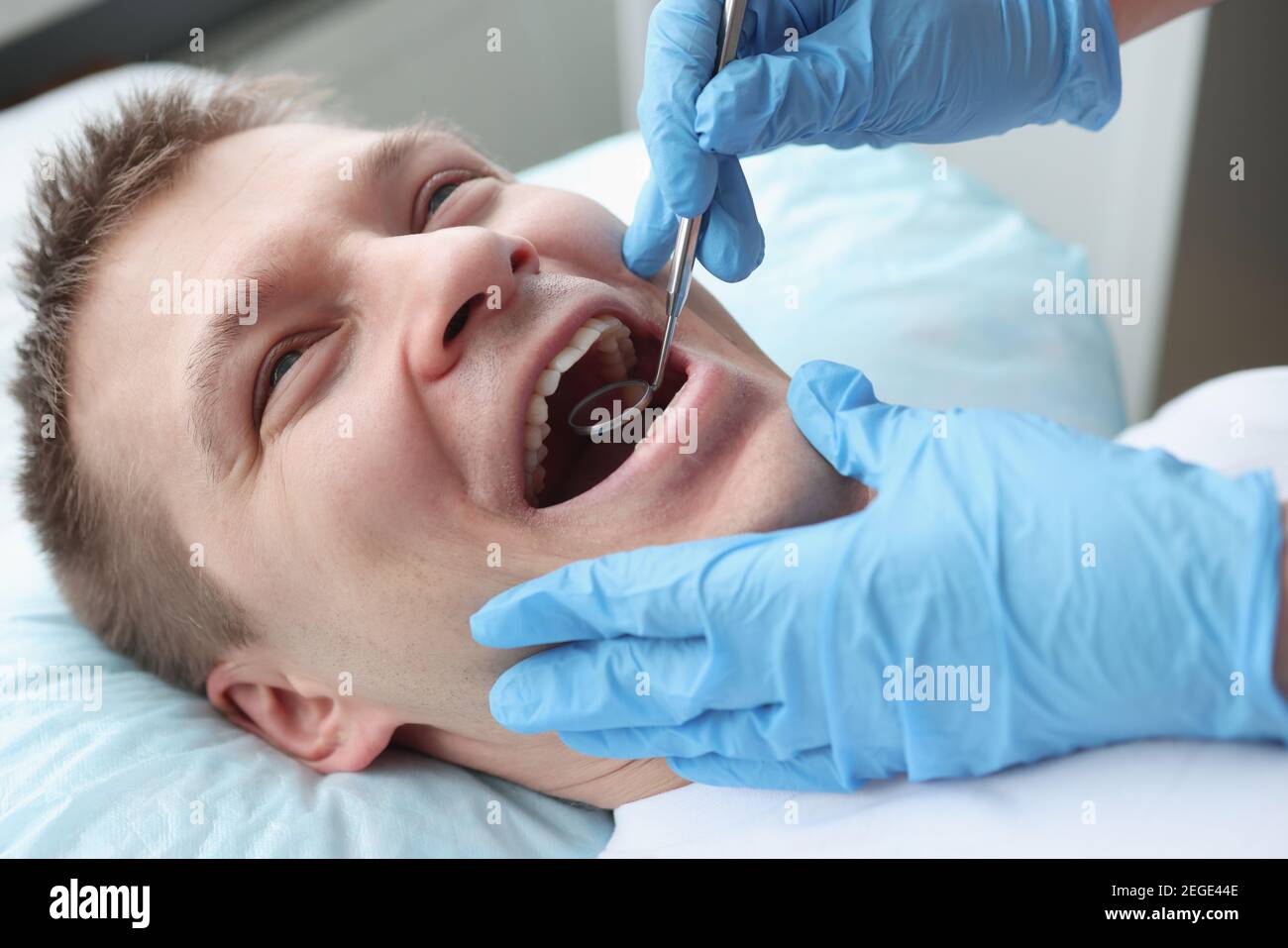 Zahnarzt, der Mundhöhle des männlichen Patienten mit Spiegel untersucht Stockfoto Zahnarzt, der Mundhöhle des männlichen Patienten mit Spiegel untersucht Stockfoto