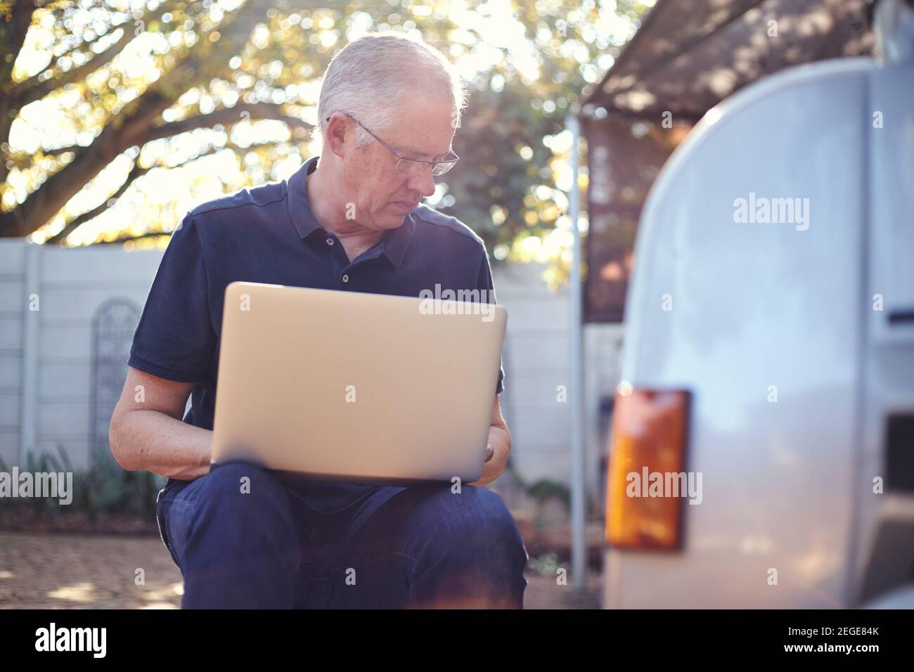 Der Mechaniker des Inhabers eines kleinen Unternehmens überprüft die Konten auf dem Laptop draußen Stockfoto