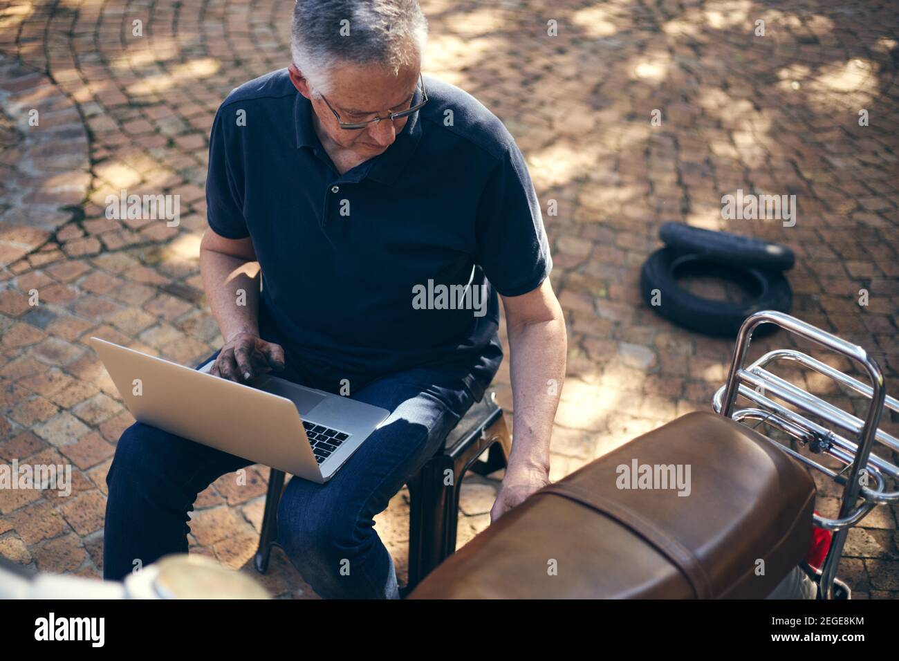 Kleinunternehmen Besitzer Mechaniker mit Laptop zu helfen, Fahrrad zu reparieren Stockfoto