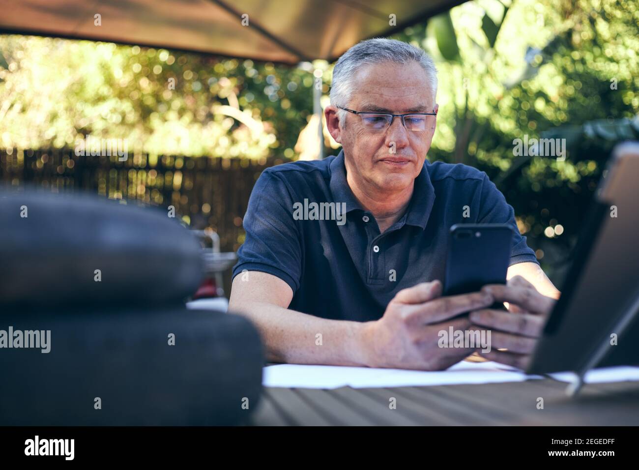 Inhaber eines kleinen Unternehmens, der am Laptop arbeitet, mit Workshop im Hintergrund Auf dem Mobiltelefon Stockfoto