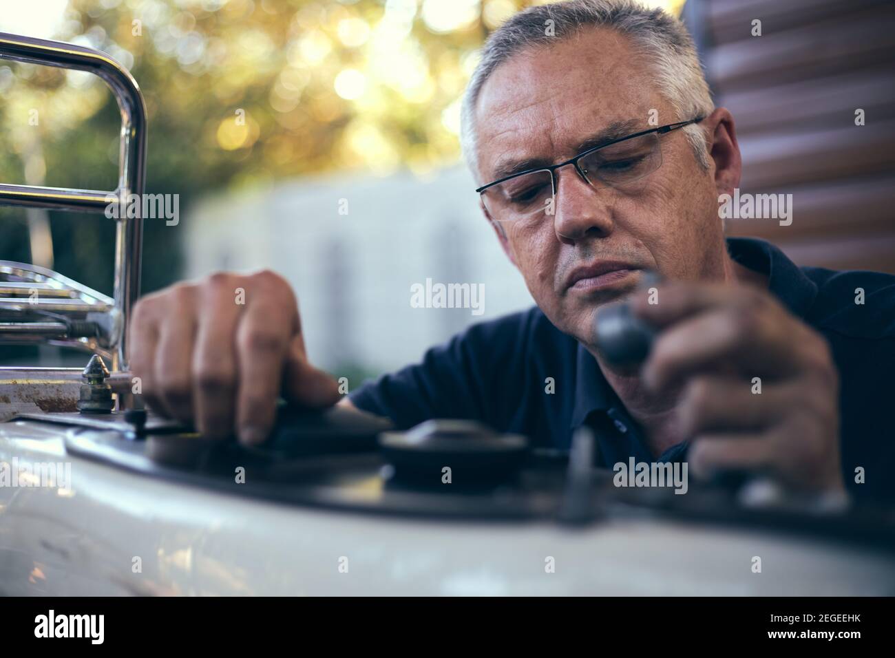 Kleiner Geschäftsmechaniker, der außerhalb der Werkstatt am Fahrrad arbeitet Stockfoto