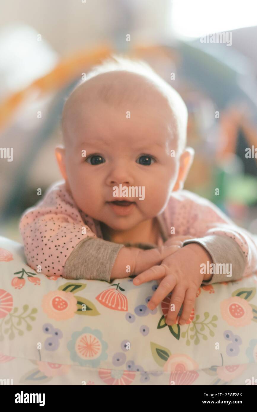 Drei Monate alt Baby Mädchen hält sich auf ein Kissen Stockfoto