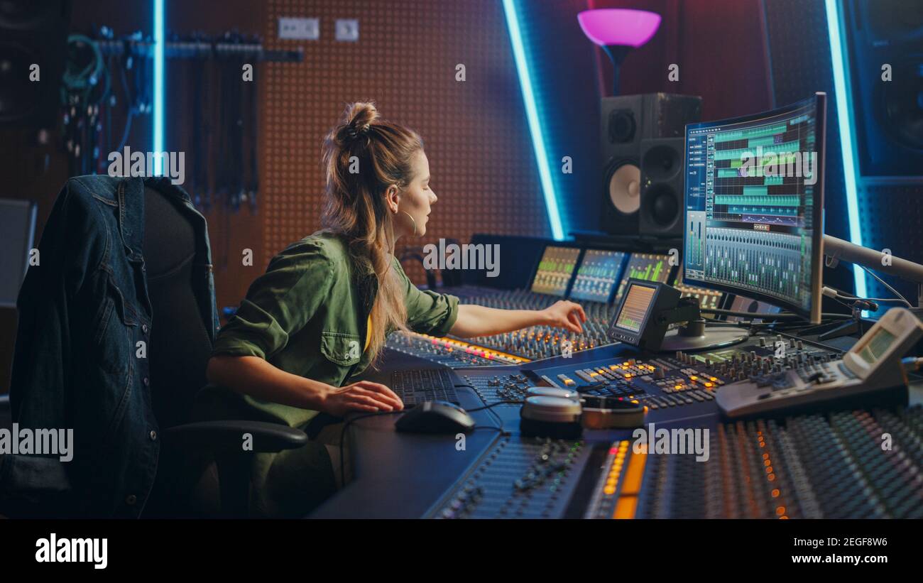 Schöne weibliche Audio-Ingenieurin arbeitet in Music Recording Studio, verwendet Mixing Board und Software, um modernen Sound zu erstellen. Creative Girl Artist Stockfoto