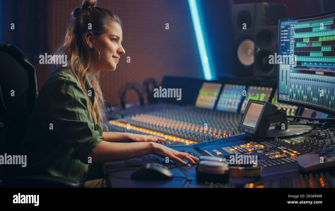 Stilvolle, schöne weibliche Audio-Ingenieurin arbeitet in Music Recording Studio, verwendet Mixing Board Create Song. Portrait eines Mädchens Künstler Musiker arbeiten Stockfoto