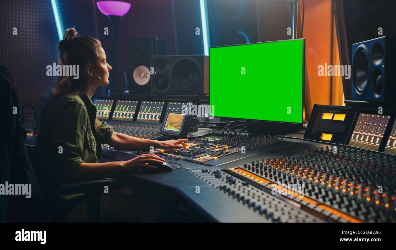 Portrait der stilvollen weiblichen Audio Engineer Producer arbeitet in Music Record Studio, verwendet Green Screen Computer, Mixer Board, Control Desk, um neue zu erstellen Stockfoto