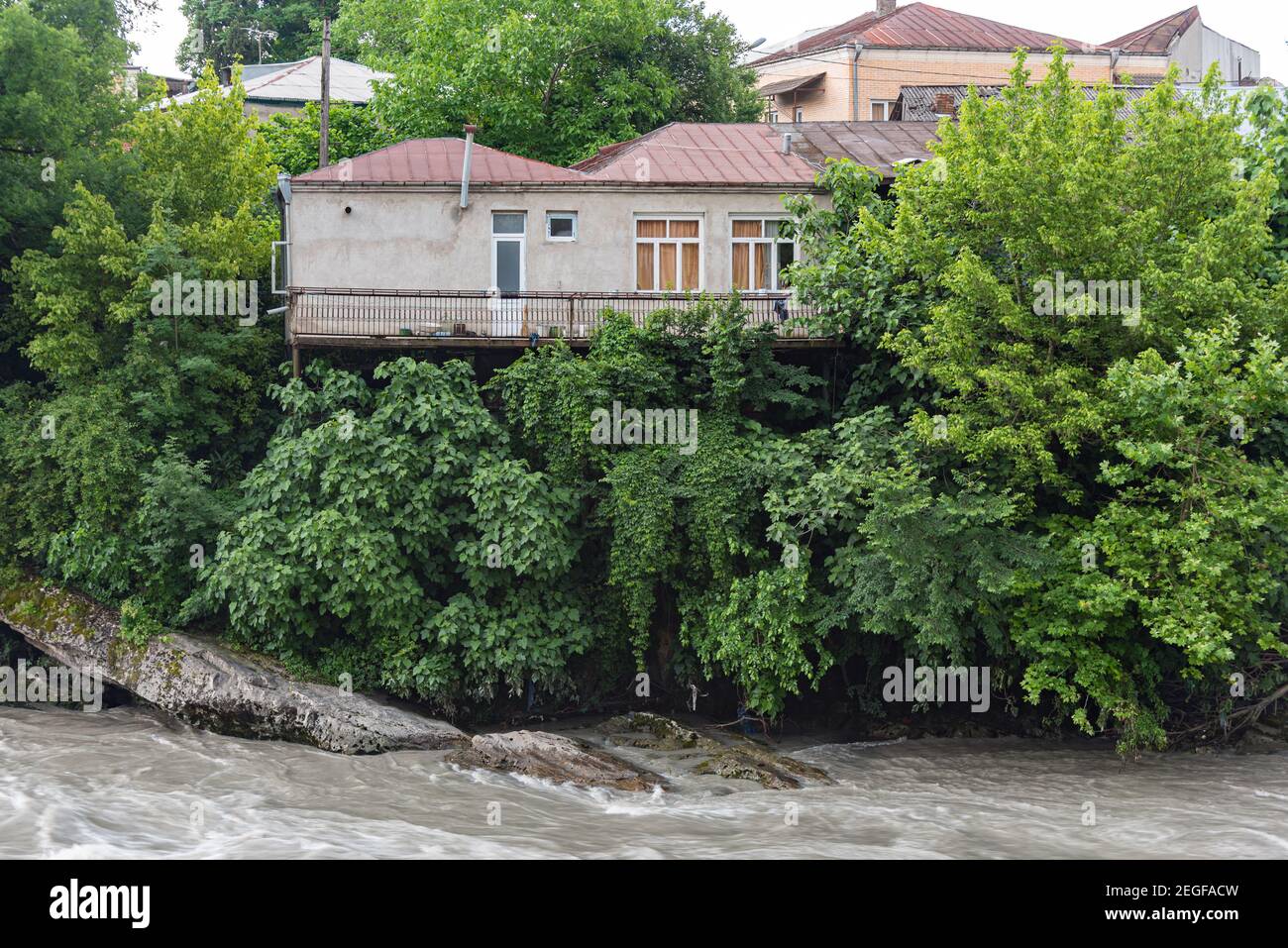 Haus mit Balkon über dem rauhen Wasser des Rioni-Flusses, Kutaisi, Georgien. Stockfoto