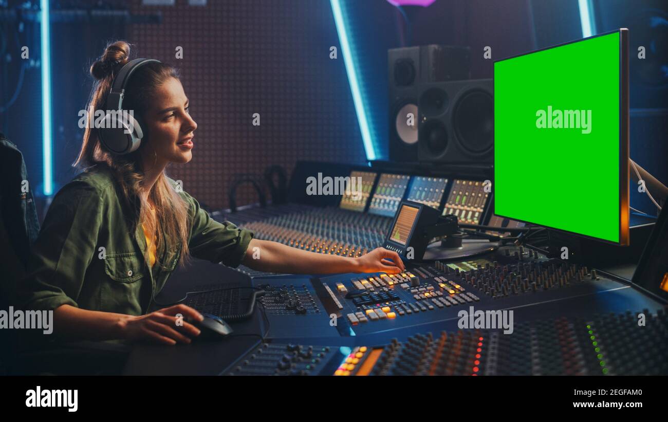 Stilvolle weibliche Audio-Engineer Producer arbeitet in Music Record Studio, verwendet Kopfhörer, Green Screen Computer Display, Mixer Board, Control Desk zu Stockfoto