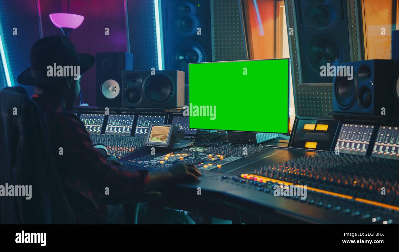 Stilvoller Audio Engineer Producer, der in Music Record Studio arbeitet, verwendet Chroma Key Computer Display, Mixer Board Equalizer und Control Desk Stockfoto