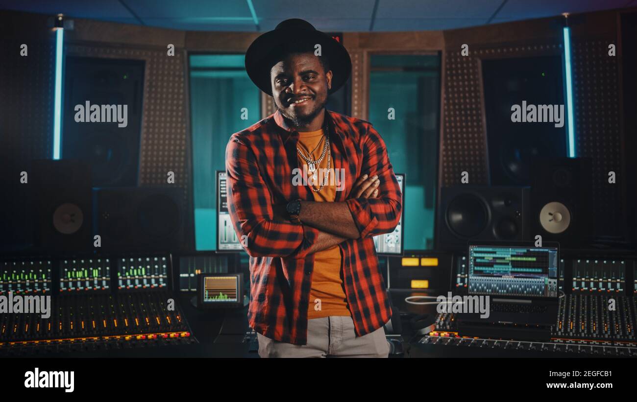 Portrait des jungen schwarzen Künstlers, Musikers, Toningenieurs, Produzenten mit stilvollem Hut und Standing im Music Record Studio. In der Hintergrundsteuerung Stockfoto