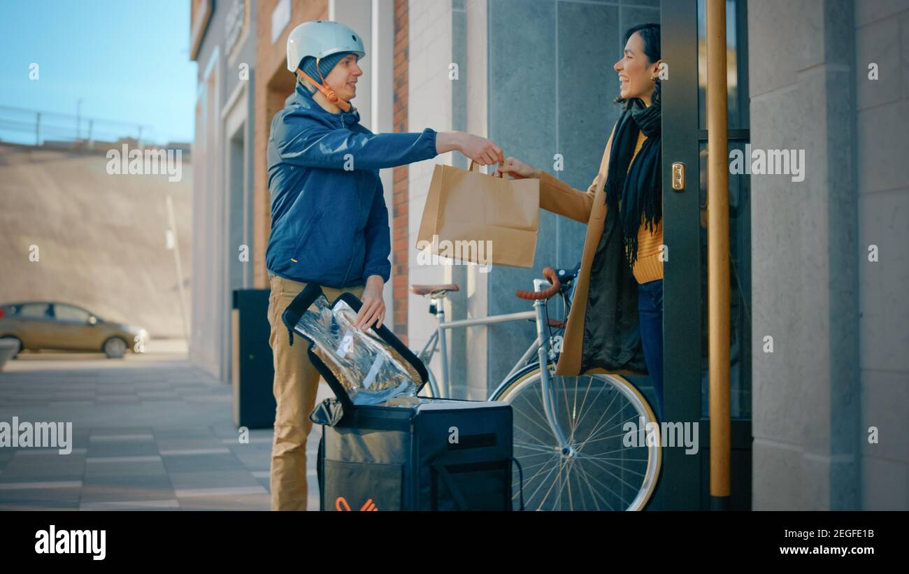 Happy Food Delivery Mann trägt thermischen Rucksack auf einem Fahrrad liefert Restaurant Bestellung an eine schöne weibliche Kunden. Kurier Liefert Takeaway Lunch Stockfoto