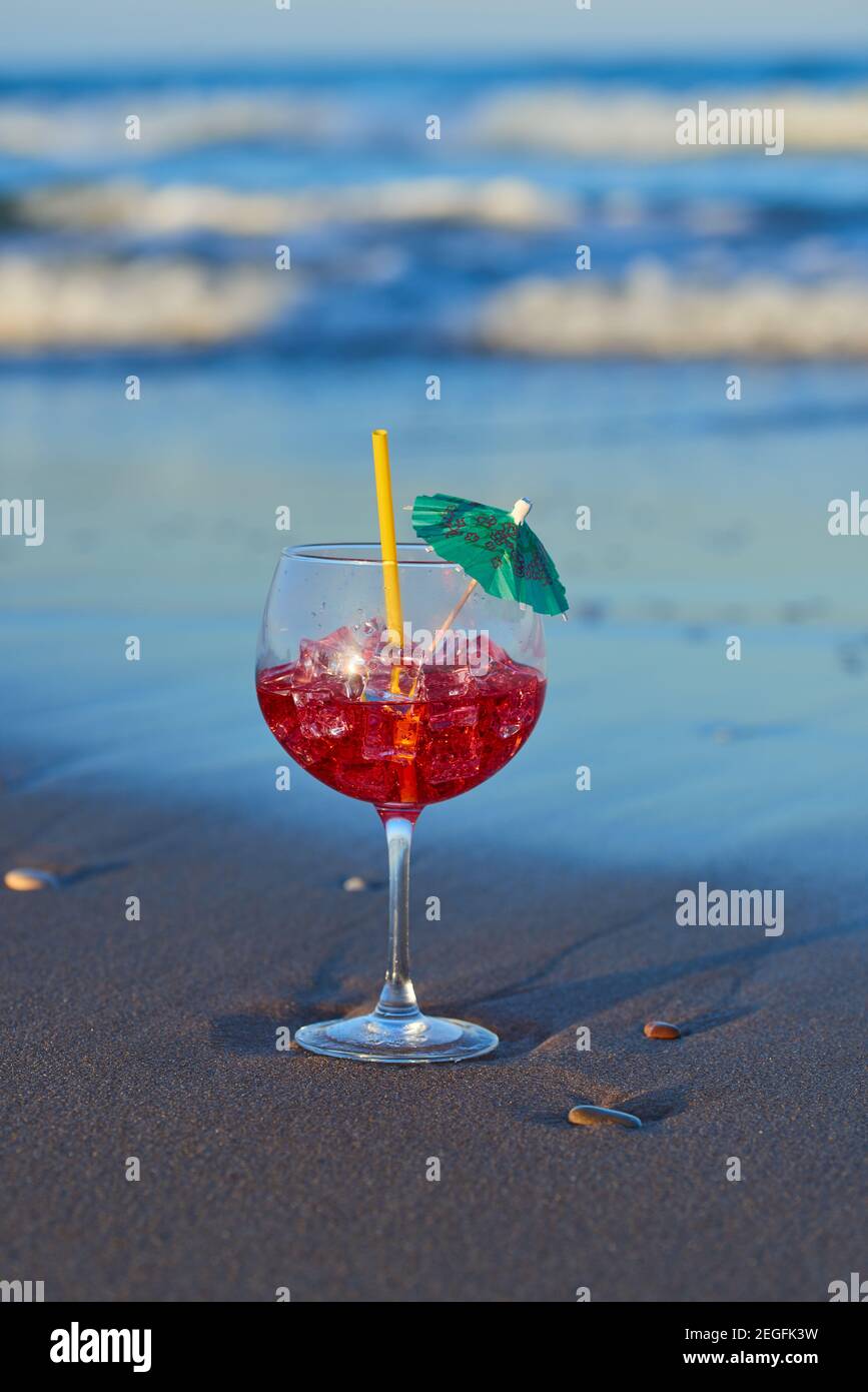 Ein köstlicher und erfrischender Cocktail auf dem Sand des Strandes in der Nähe der Wellen. Stockfoto