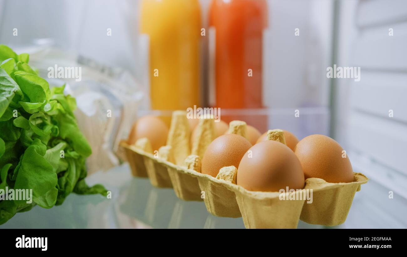Shot aus der Küche Kühlschrank: Box Pack von Eiern, frischen Säften und grünem Gemüse. Point of View POV Aufnahme aus Kühlschrank voller Gesundheit Stockfoto