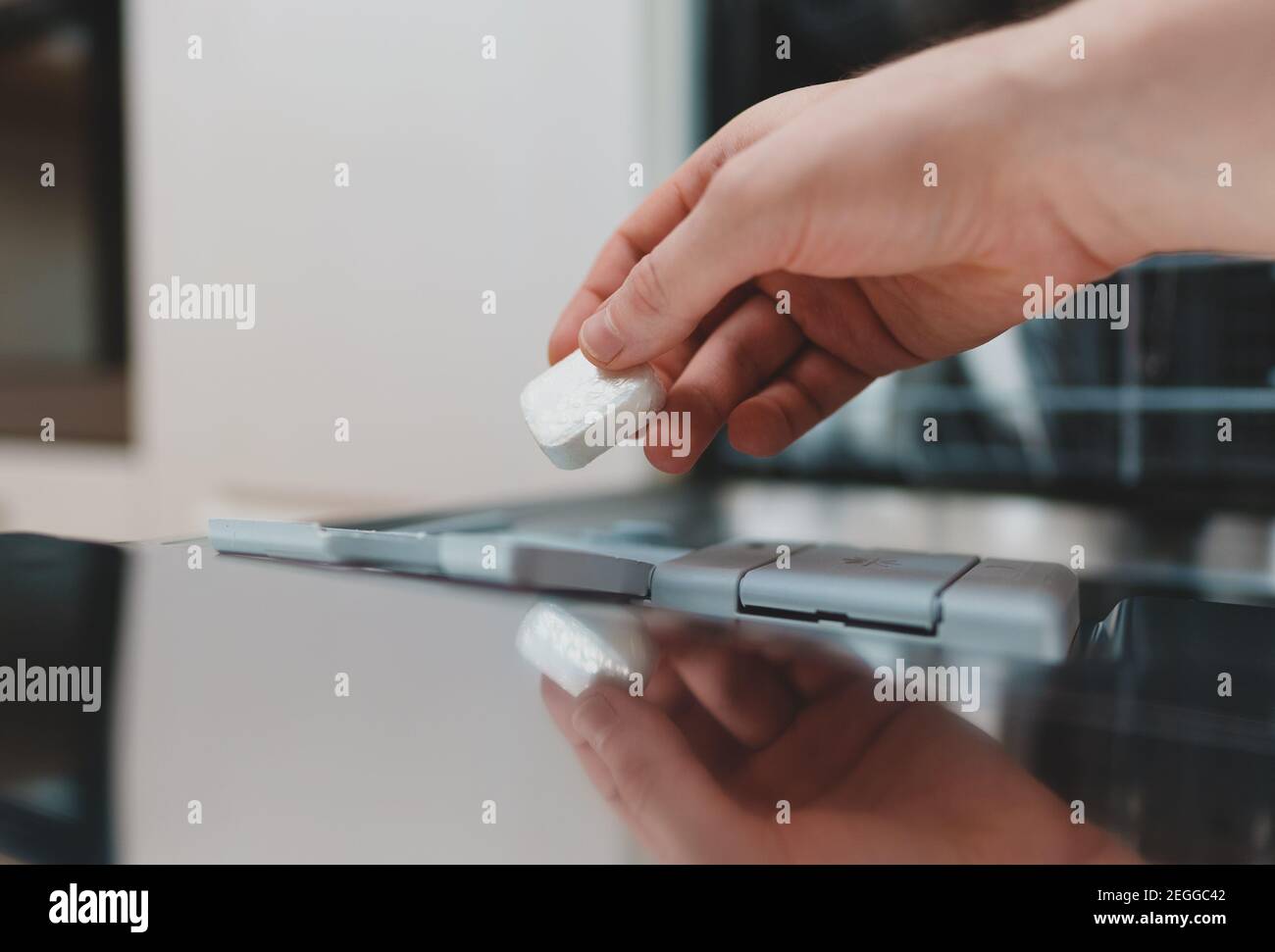 Mann, der Waschmitteltablett in die Spülmaschine legte. Stockfoto