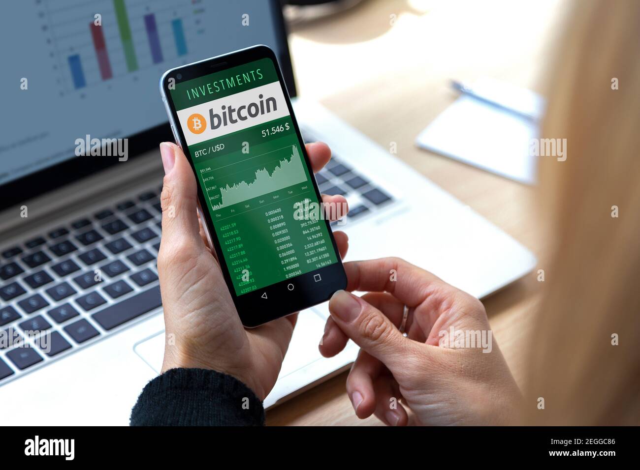 ROSARIO, ARGENTINIEN - 17. FEBRUAR 2021: Bitcoin-Diagramm in einem Bildschirm des Mobiltelefons. Geschäftsfrau mit Smartphone in den Händen. Investition in virtuelles Geld Stockfoto