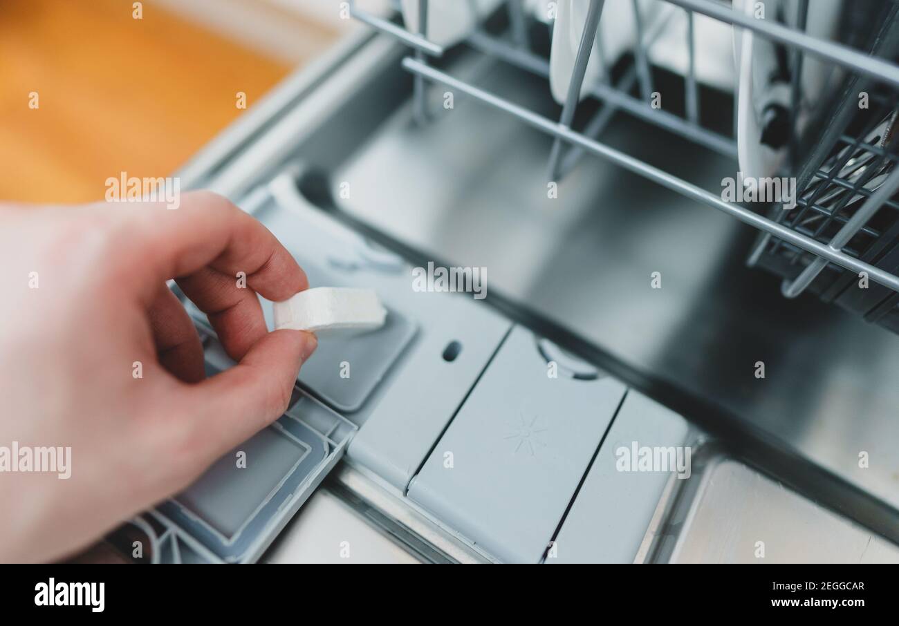 Mann, der Waschmitteltablett in die Spülmaschine legte. Stockfoto